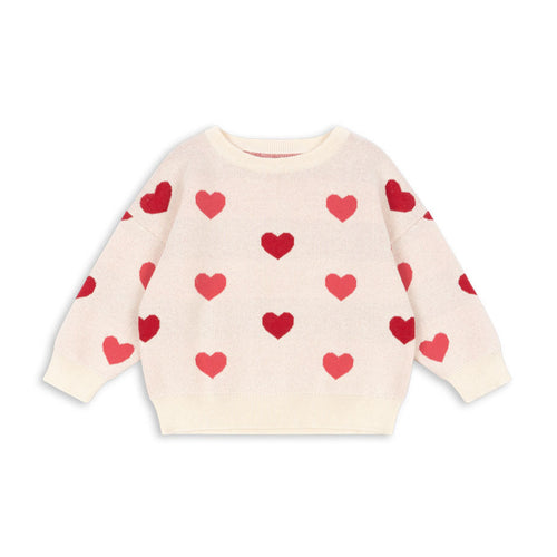 Cream-colored sweater with red heart patterns on a white background