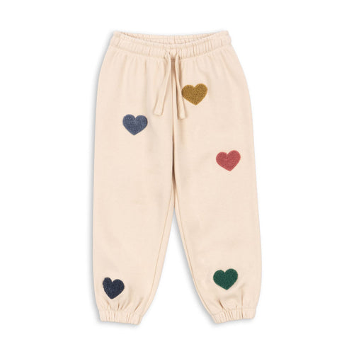 Beige sweatpants with colorful heart patterns on a white background