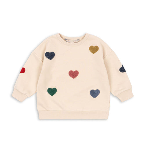 Beige sweatshirt with colorful heart patterns on a white background