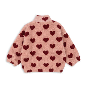 Pink fleece jacket with red heart patterns on a white background