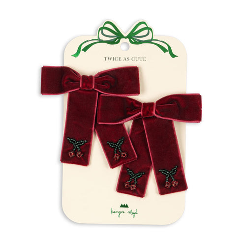 Set of red velvet bows with green details on a decorative card.