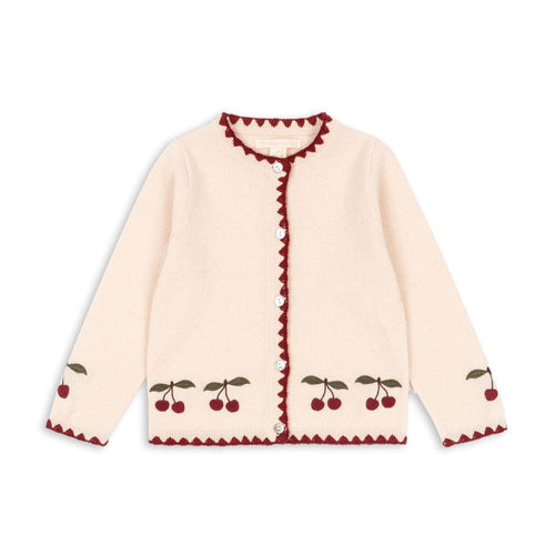 Cream-colored cardigan with red trim and cherry patterns on a white background