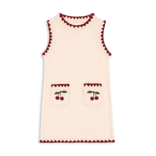 Cream-colored sleeveless top with red trim and cherry designs on a white background