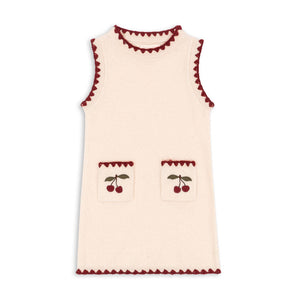 Cream-colored sleeveless top with red trim and cherry designs on a white background