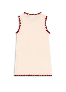 Cream-colored sleeveless top with red trim on a white background
