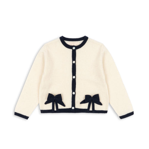 Cream-colored cardigan with black bow details on a white background