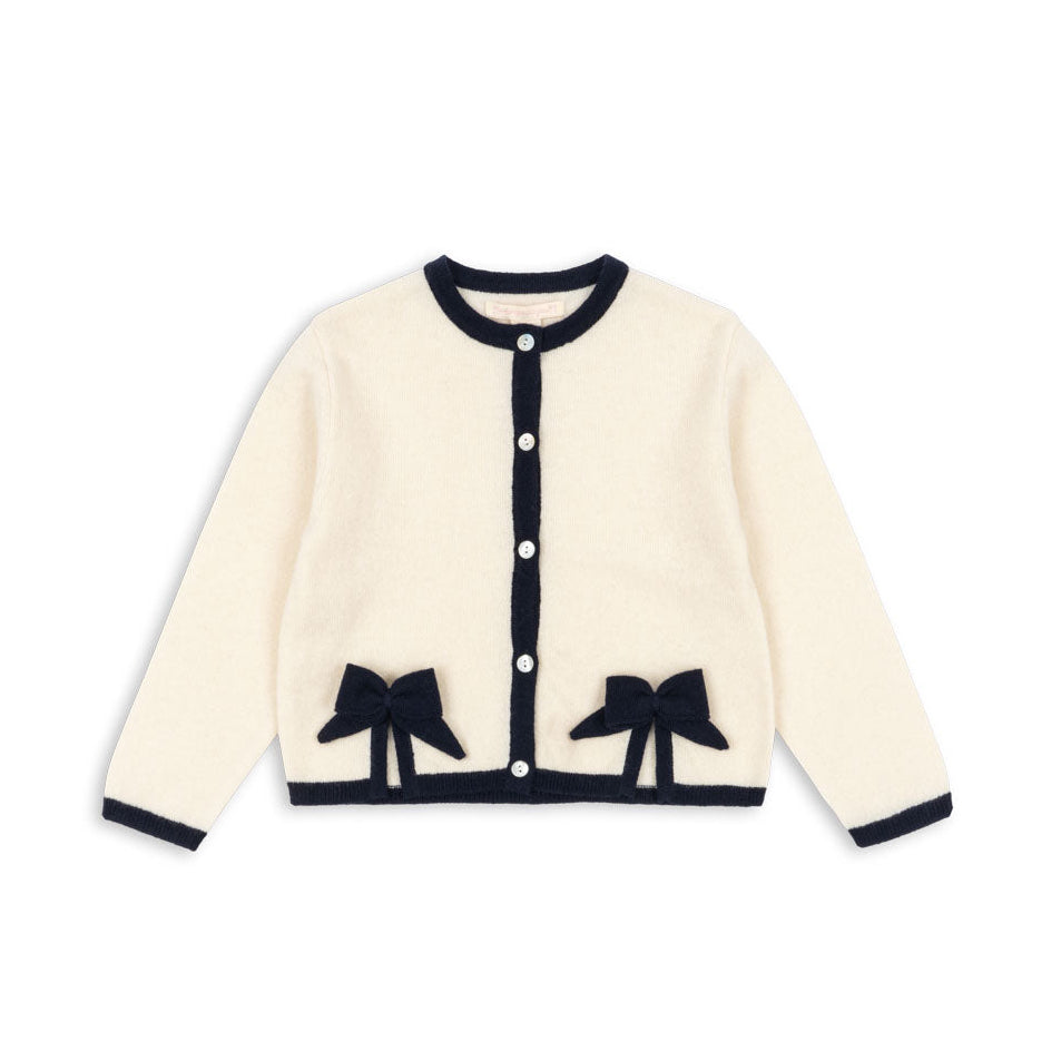 Cream-colored cardigan with black bow details on a white background