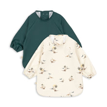 將圖片載入圖庫檢視器 Two children's smocks, one green and one cream with floral pattern, on a white background.