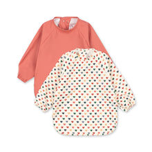 Load image into Gallery viewer, Two baby bibs, one coral and one with heart pattern, on a white background