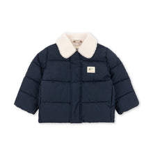 將圖片載入圖庫檢視器 A navy blue puffer jacket with a cream-colored faux fur collar, featuring horizontal quilting and a small rectangular brand patch on the left chest, displayed against a solid white background.