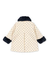 Load image into Gallery viewer, A cream-colored children's coat with a black polka dot pattern, featuring dark navy faux fur trim on the collar and cuffs, shown from the back against a white background.