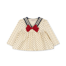 Load image into Gallery viewer, A cream-colored long-sleeve baby top with black polka dots, featuring a navy and cream striped collar and a red bow at the center of the neckline.