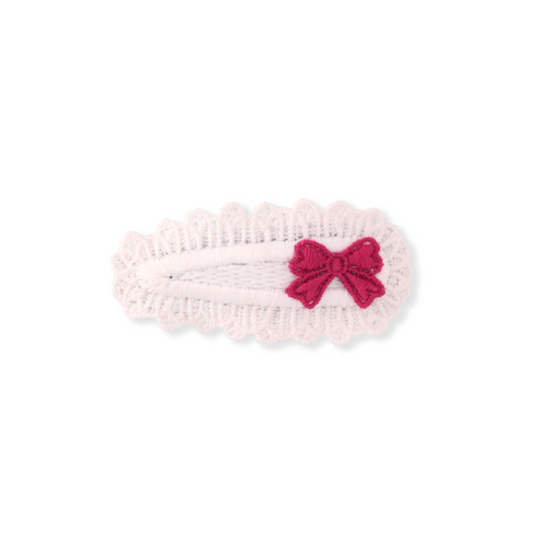Pink knitted headband with a red bow on a white background