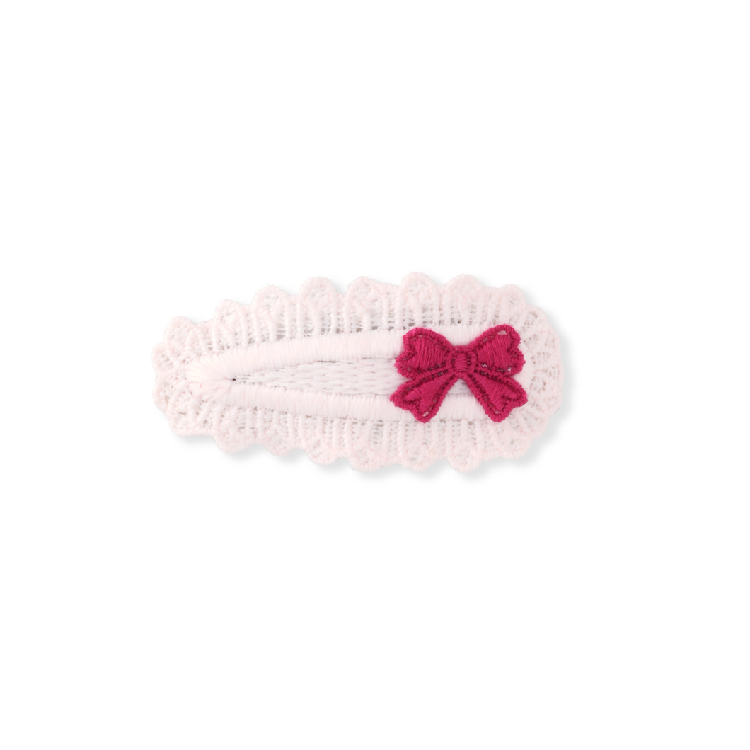 Pink knitted headband with a red bow on a white background